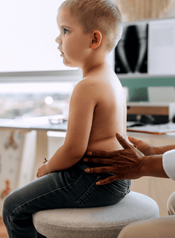 A young boy having his spine checked by a health professional